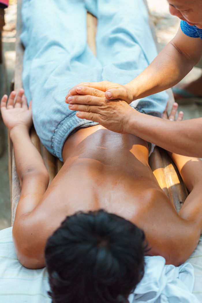 quality-assurance-02 A person receiving a traditional massage outdoors on a sunny day.