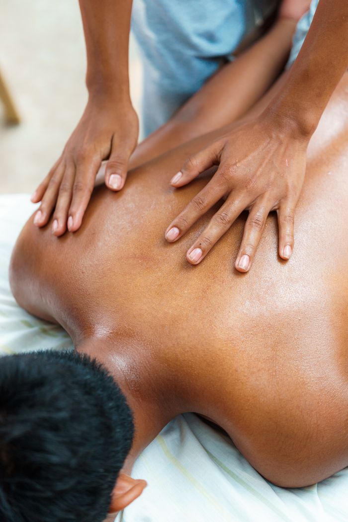 Therapist giving a professional massage to a client lying face-down indoors.